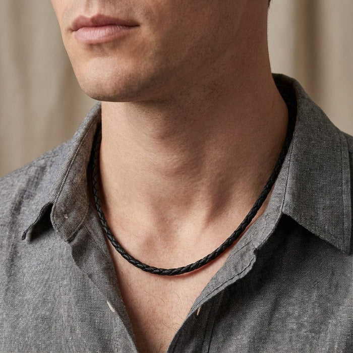A close-up editorial photography of a man wearing a 22-inch long 3mm black braided leather necklace cord.