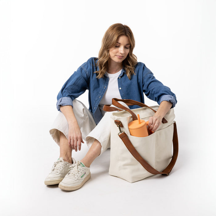Cream-colored interior space with warm brown leather furniture, denim blue accents, and a vibrant orange highlight detail