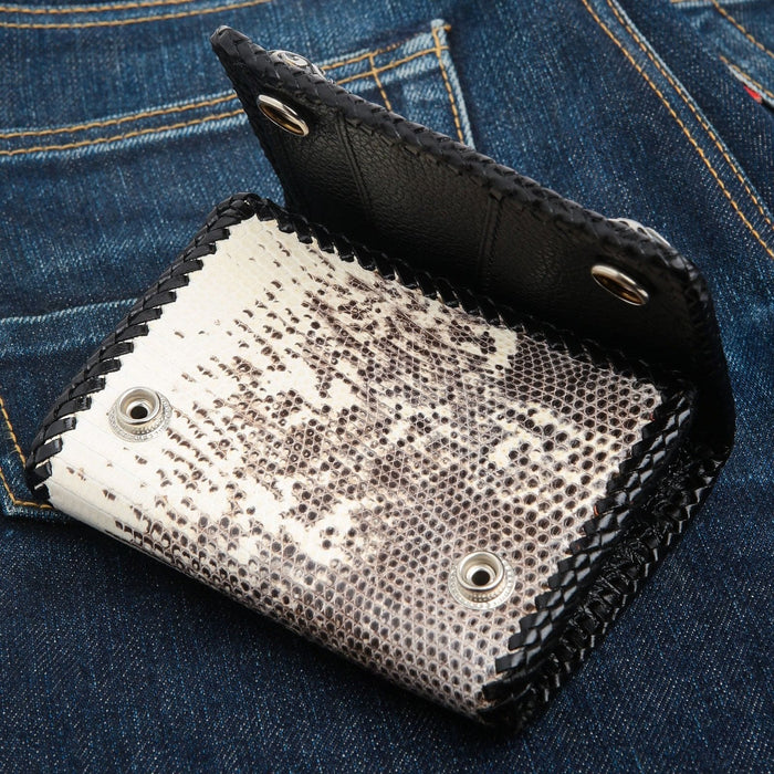 Partly unfolded wallet showing the lizard skin panel, black cowhide flap and two silver snap fasteners.