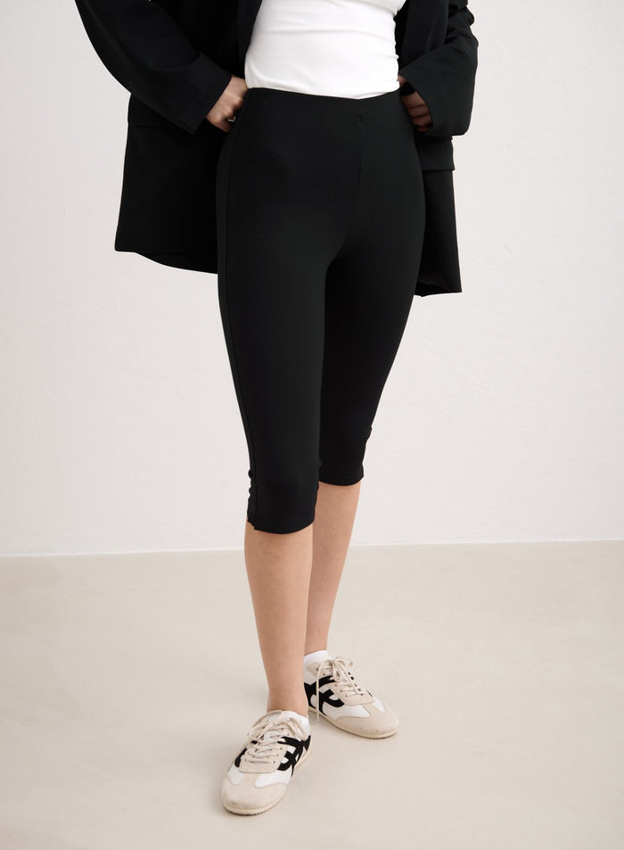 Black high-waisted aim'n Luxe Capri Pants styled with a blazer and sneakers. [34-174cm]