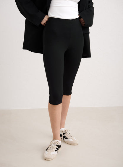 Black high-waisted aim'n Luxe Capri Pants styled with a blazer and sneakers. [34-174cm]