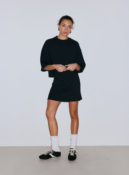 A female model wearing a black oversized top and a black mini skort, white socks, and sneakers. [36-170CM]