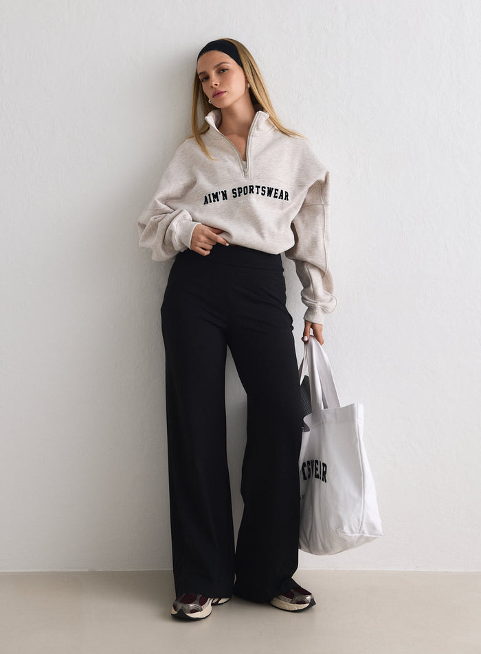 Model wearing Black Sense Pants and a beige half-zip sweatshirt, holding a white tote bag [M-170cm]