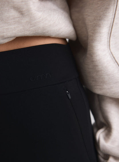Close-up of black Sense Pants featuring a high waist with aim'n logo and a zipped pocket [M-170cm]