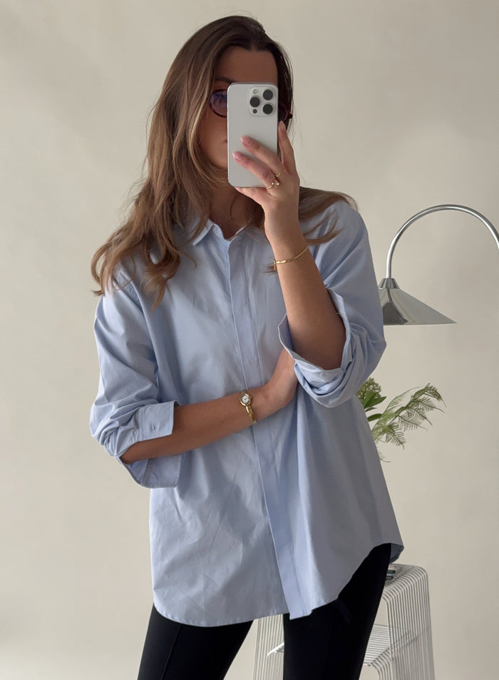 Woman taking a mirror selfie in a blue Oxford shirt from aim'n [S-171cm]
