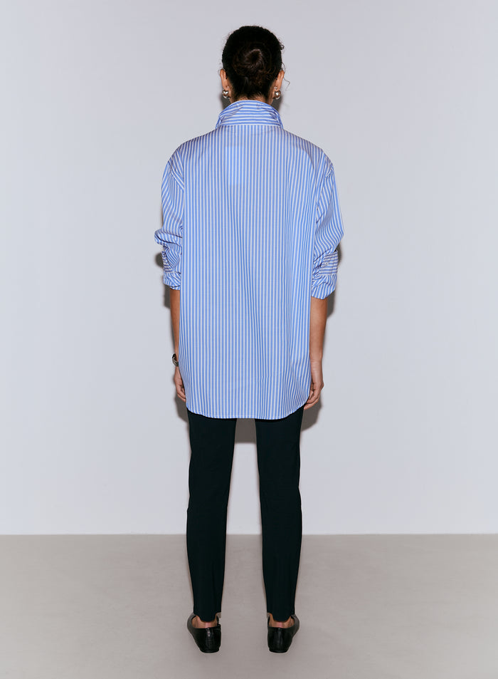 A model seen from the back wearing a blue and white striped poplin shirt with rolled-up sleeves and dark trousers [M-170CM]