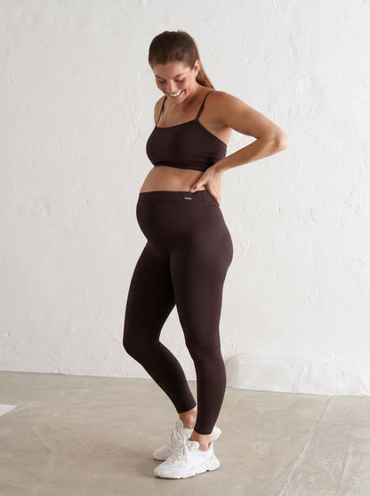 Cacao ribbed seamless maternity tights by aim'n with a high waistband worn by a smiling pregnant woman.