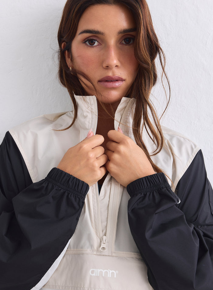 Close-up of a beige and black color-block aim'n windstopper jacket with a half-zip collar [S-165cm]