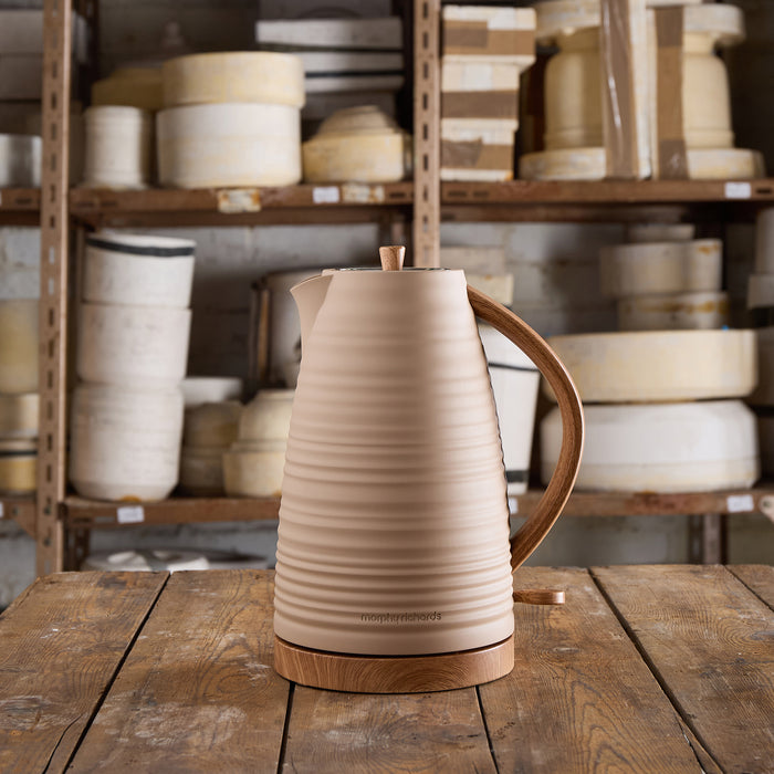 Beige electric kettle with wooden handle on a wooden table in a warehouse setting