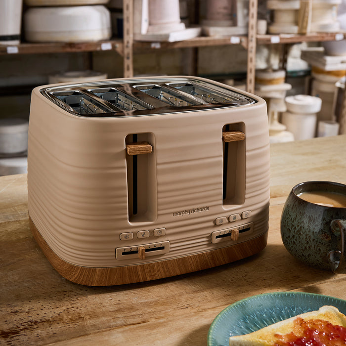 Beige toaster on a wooden table with a cup of coffee and plate in a kitchen setting