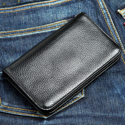 Black pebbled cowhide with edge stitching, the closed chain wallet lying against blue denim.
