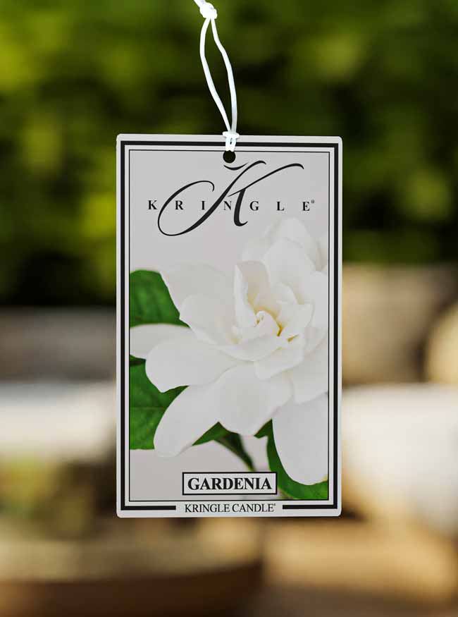 Kringle Candle Gardenia fragrance tag with a white flower on a blurred background