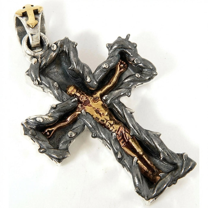 Angled view of oxidized sterling silver thorn cross pendant showing golden Christ figure detail