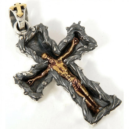 Angled view of oxidized sterling silver thorn cross pendant showing golden Christ figure detail