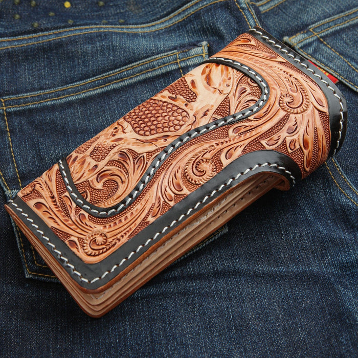 The tooled leather demon wallet folded in a back pocket, showing the intricate floral carving and black border.