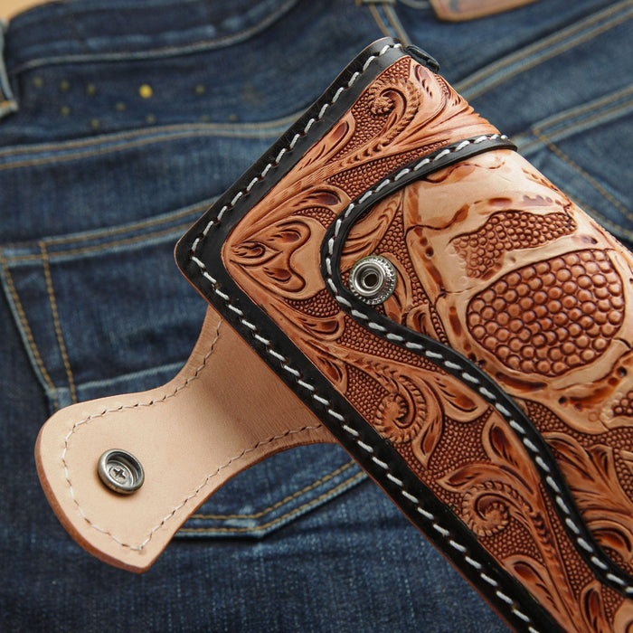 A close-up of the unfastened snap and silver concho on the tooled leather biker wallet.