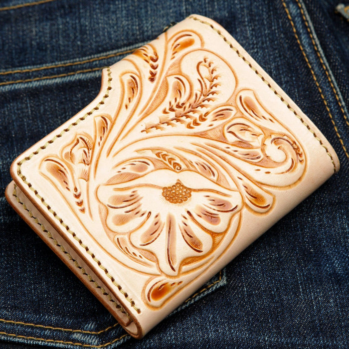 Deep floral carving darkened in the recesses stands out on light tan leather, edged in pale stitching.