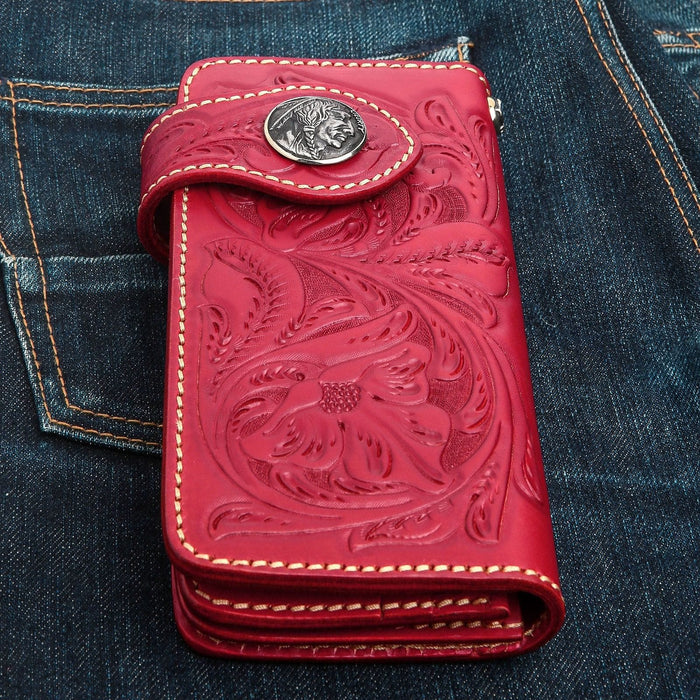 A long, red leather biker wallet with intricate floral carvings, shown on the back pocket of jean.