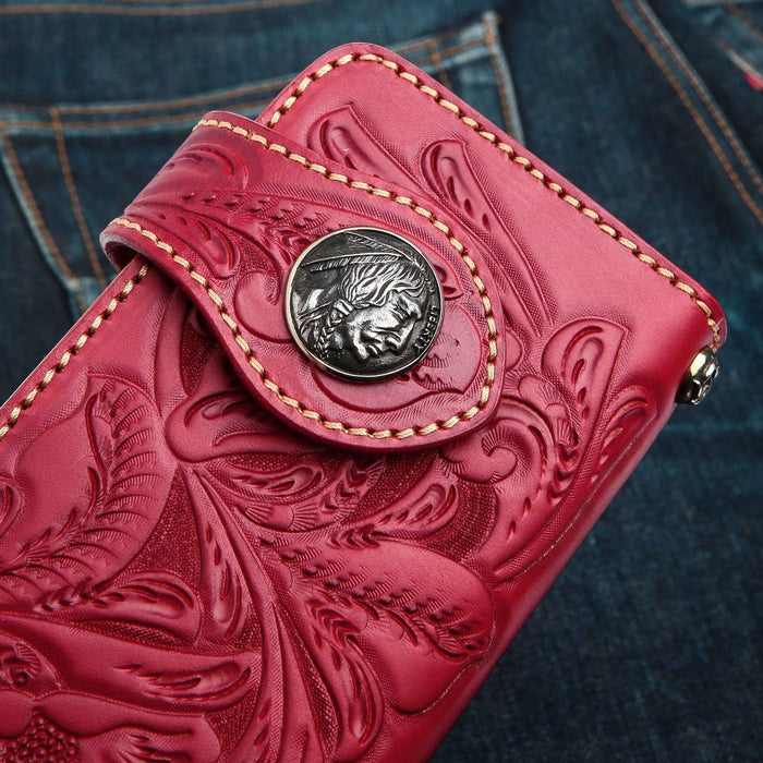 A close-up detail shot of the classic silver Indian Head concho on a vibrant red, hand-tooled leather wallet.