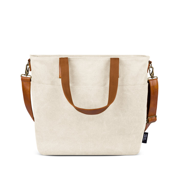 Cream-colored crossbody bag with cognac brown leather handles and accents