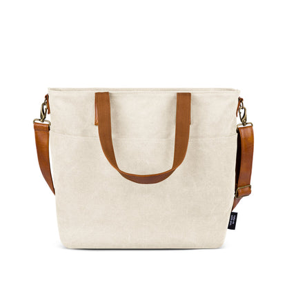 Cream-colored crossbody bag with cognac brown leather handles and accents