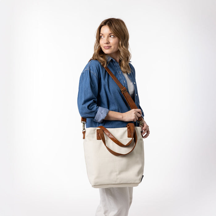 Medium blue denim fabric next to warm cream canvas and rich cognac brown leather swatches on neutral background