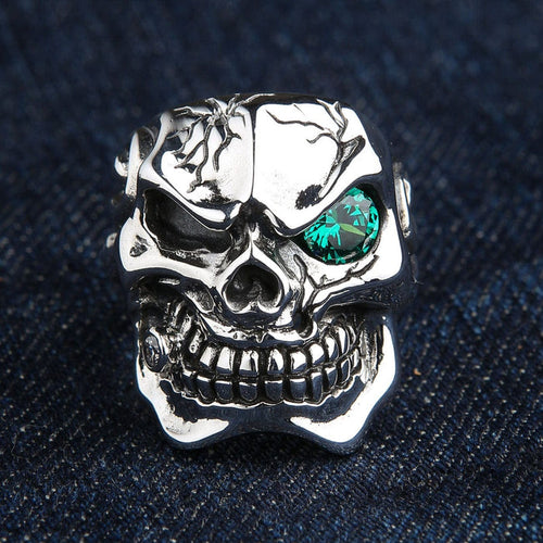 A heavy sterling silver cracked skull ring for men with a piercing emerald green CZ eye.