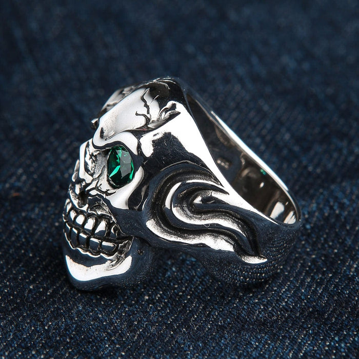 A rocker-style skull ring with a brilliant emerald green eye, handcrafted in sterling silver.