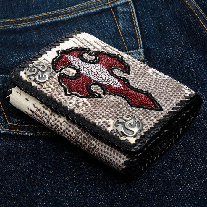 Angled view of the natural lizard skin biker wallet with red stingray cross inlay and braided black leather edge, resting on blue denim.