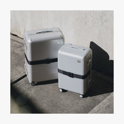 Olive Green | Front view of two different sizes of Aluminum suitcases on the street with the Midnight Black Luggage Strap secured around them