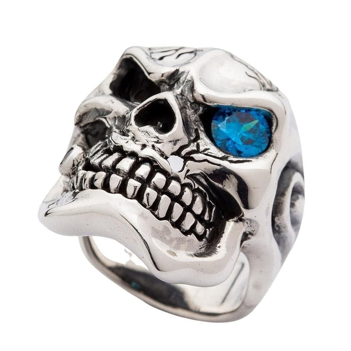 Angled view of heavy silver skull ring displaying blue topaz eye and detailed teeth