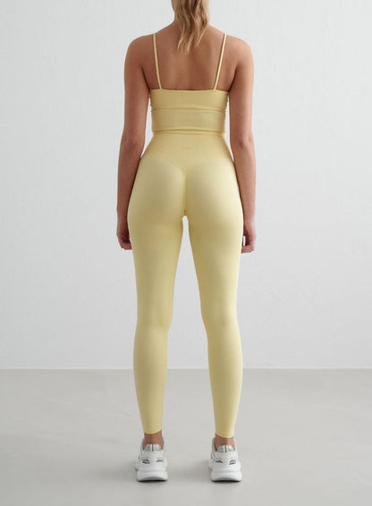 Mellow yellow aim'n Shape Seamless Tights feature an invisible scrunch and high ribbed waist in this rear view.