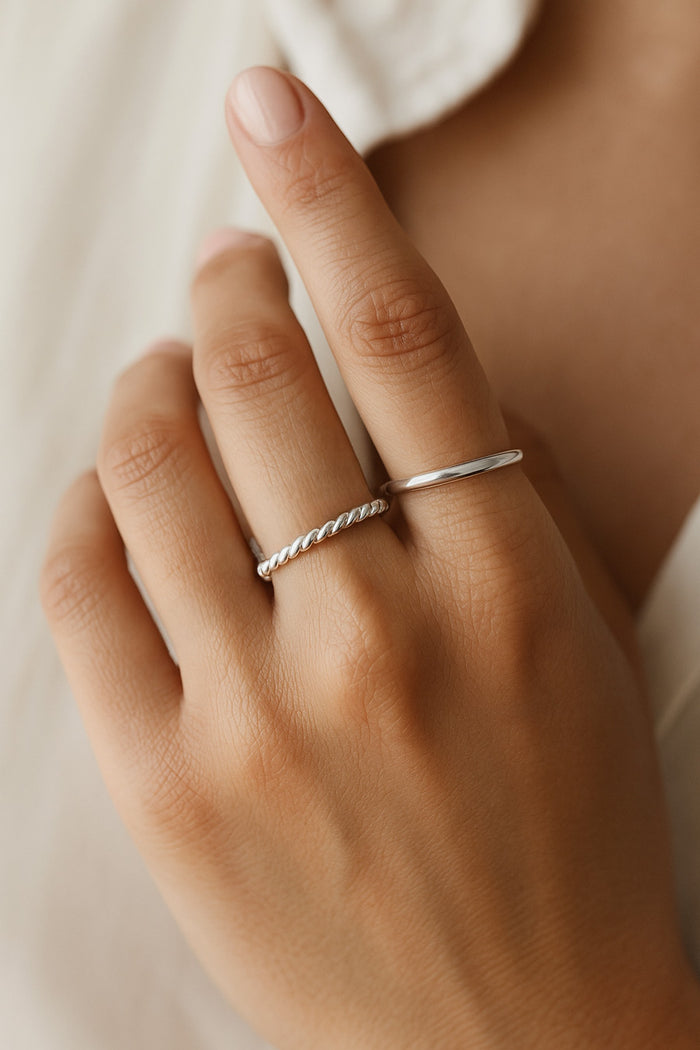 Kvinna som bär två smala silverringar. En vriden silverring och en blank slät silverring.