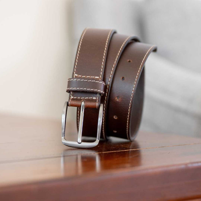 nickel free silver belt buckle with brown leather strap 1.5 inch wide with cream stitching.