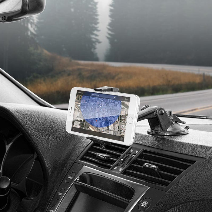 A smartphone shows a map while secured in the Mobile Grip 2 Phone Car Mount with Sticky Suction on the dashboard. The car is parked by the road, and trees along with a foggy forest are seen through the windshield.