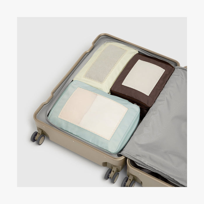 Set of Four / Multi | Top view of Monos x Reformation compressible packing cubes in Multi color neatly organized inside a Hybrid suitcase in Champagne