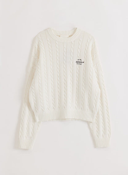 Off-white cotton cable knit sweater from aim'n with a crew neck and logo detail in a flat lay style.