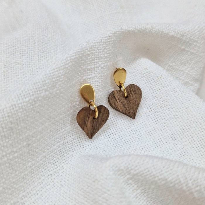 Handgefertigte Holzohrringe in kleiner Herzform und goldenem Stecker auf weißem Hintergrund