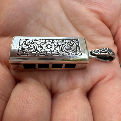 The engraved sterling silver harmonica pendant, showing the beautiful floral motif.