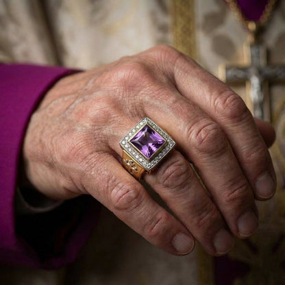 Elegant princess-cut amethyst bishop ring with diamond halo setting in gold, worn on a clergy member's hand with purple vestment sleeve and silver cross visible in background