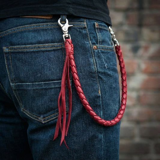 Red burgundy braided leather wallet chain with silver metal clips attached to blue denim jeans back pocket featuring decorative leather tassels