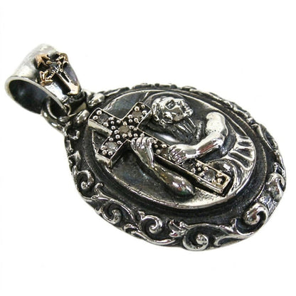 Angled close-up showing the 3D relief of a saint grasping a CZ-lined cross, framed by an ornate oxidized silver border.