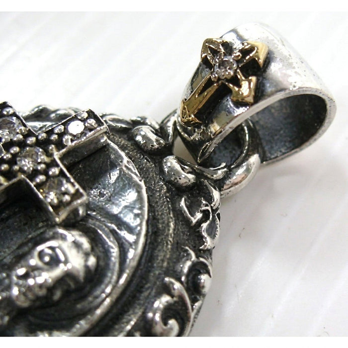 Macro view highlighting the ornate silver pendant bail adorned with a miniature gold-tone cross and clear center stone.