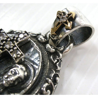 Macro view highlighting the ornate silver pendant bail adorned with a miniature gold-tone cross and clear center stone.