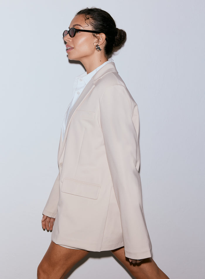 Woman wearing a sand Luxe Relaxed Blazer and sunglasses, looking to the left [40-170CM]