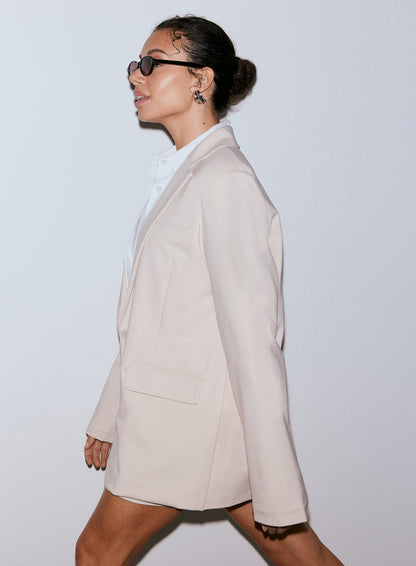 Woman wearing a sand Luxe Relaxed Blazer and sunglasses, looking to the left [40-170CM]