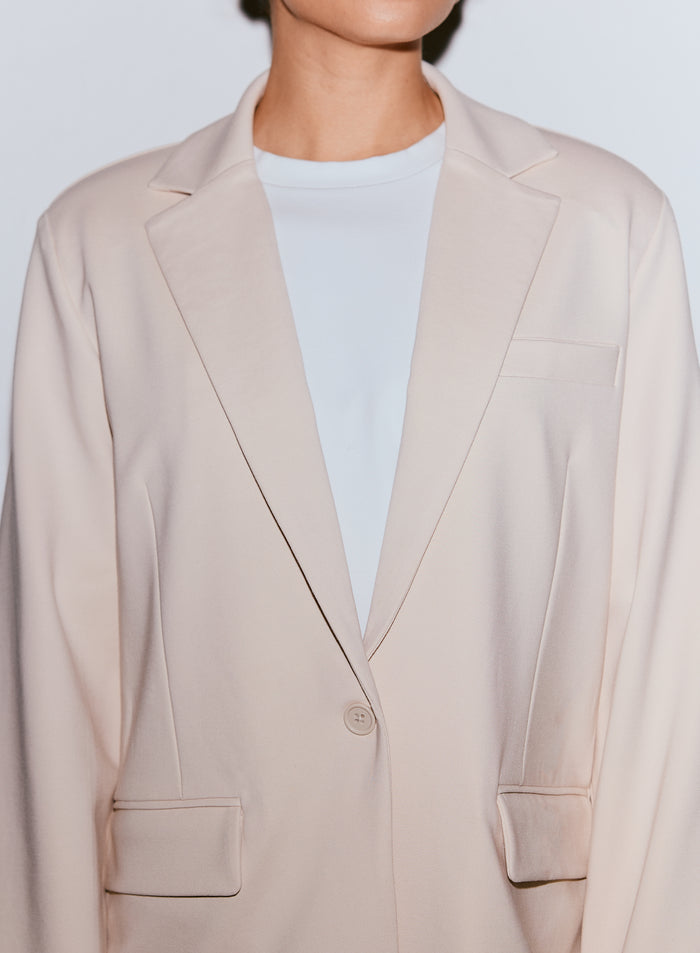 Close-up of a person wearing a sand Luxe Relaxed Blazer over a white t-shirt [40-170CM]