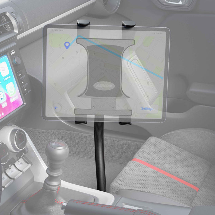 A tablet is held by the Slim-Grip® Tablet Holder with Seat Rail Mount and 22 Bendable Arm, displaying a map app next to the center console. The car’s interior also shows the gear shift, part of the dashboard, and a red-striped seat.