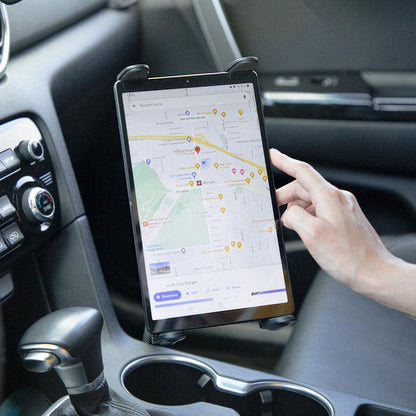 Using the Slim-Grip® Tablet Holder with Seat Rail Mount and 22 Bendable Arm, a person secures their tablet in the car to view navigation apps, with the dashboard and gear shift also visible.
