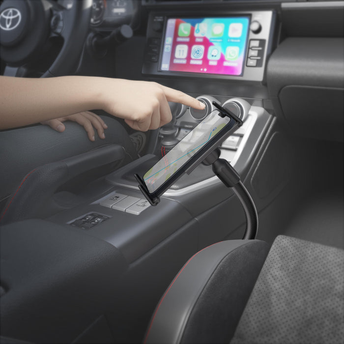 A person interacts with a smartphone secured in a Slim-Grip® Ultra 18″ Seat Rail or Floor Car Mount inside a car, with a navigation map shown on the phone’s screen and the car’s infotainment system visible in the background.